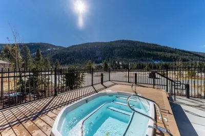 a hot tub on a deck next to a fence at Clearwater Lofts Luxury 1 Bed Condo Near Lakeside Village in Keystone