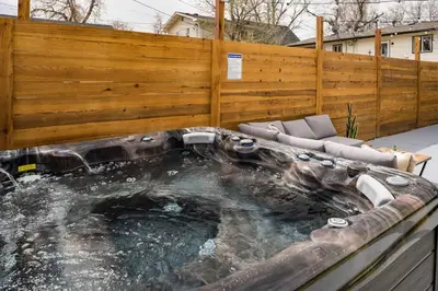 a hot tub in a backyard with a wooden fence at Wild West Disco Haus 2! New Hot Tub, Patio + Gym in Denver