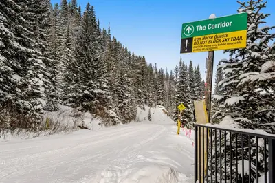 a sign on a snow covered road with trees at Iron Horse Resort D3084 in Winter Park