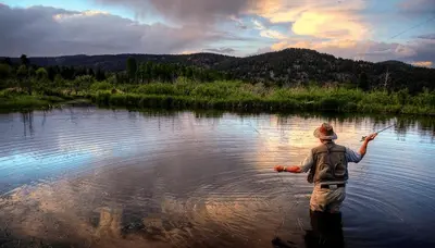 a man standing in a river holding a fish at Alpine Suite - Minutes to RMNP, Hot Tub! in Estes Park