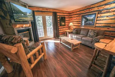 a living room with a couch and a fireplace in a log cabin at Fawn Valley Inn- 286 condo in Estes Park