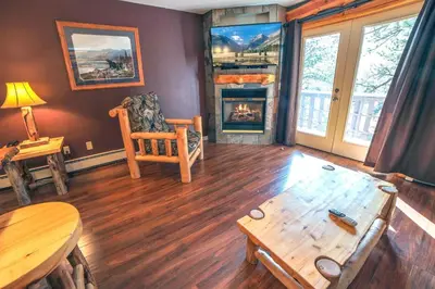 a living room with a table and a fireplace at Fawn Valley Inn- 286 condo in Estes Park