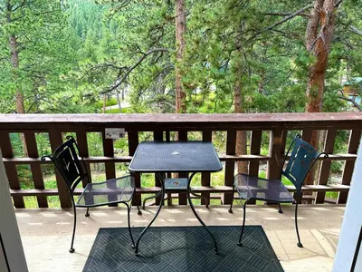 a table and chairs on a deck with trees at Fawn Valley Inn- 286 condo in Estes Park
