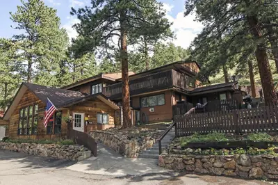 a log cabin with an american flag in front of it at Timber Creek Chalets- 10A chalet in Estes Park