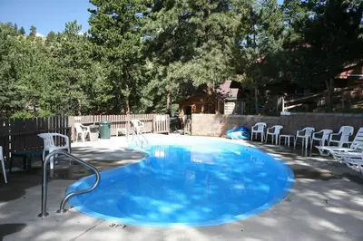 a large blue pool with chairs in a backyard at Timber Creek Chalets- 14 chalet in Estes Park