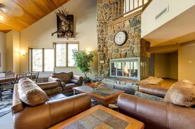 a living room with leather furniture and a stone fireplace at Ski-InandSki-Out Winter Park Condo with Mountain Views in Winter Park