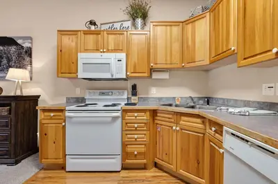 a kitchen with white appliances and wooden cabinets at Bugle Pointe A13 by Estes Park Condos in Estes Park