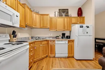 a kitchen with wooden cabinets and white appliances at Bugle Pointe A13 by Estes Park Condos in Estes Park