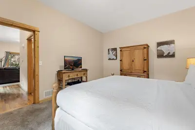a bedroom with a white bed and a television at Bugle Pointe A13 by Estes Park Condos in Estes Park