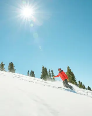 a man riding a snowboard down a snow covered slope at Beautiful 2BR in River Run - Kids Ski Free! condo in Dillon