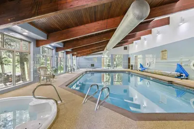 an indoor pool in a house with a tub at Winter Park Condo with Resort Shuttle On-Site! in Winter Park