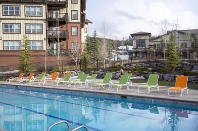 a row of lounge chairs next to a swimming pool at Base Camp 304 condo in Granby