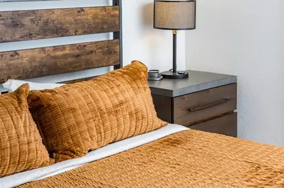 a bed with an orange blanket and a lamp on a night stand at Mountain View Apartment Near Downtown & Trails in Evergreen