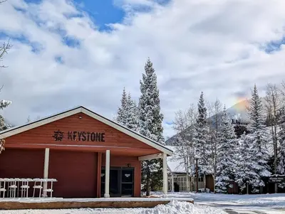 a hospice building in the snow with a rainbow in the background at Hidden River Lodge 5969 by SummitCove Lodging in Keystone