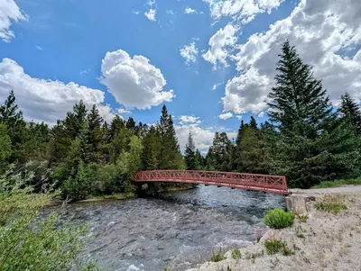 a red bridge over a river in a forest at Hidden River Lodge 5969 by SummitCove Lodging in Keystone