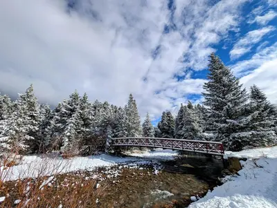 a red bridge over a river in a snow covered forest at Gateway Lodge 5003 by SummitCove Lodging in Keystone