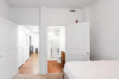 a white bedroom with a bed and a bathroom at Welcoming Hideaway Near UNC & Downtown in Greeley