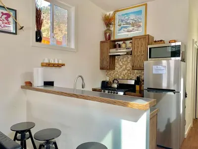 a kitchen with a refrigerator and a counter with stools at Skiers Cabin at Base Camp Lodging Company in Dumont