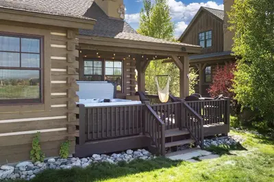 a deck with a hot tub on the side of a house at 19th Hole cabin in Granby