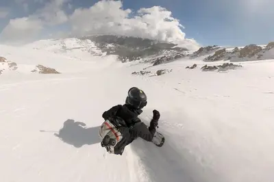 a man riding a snowboard down a snow covered slope at Trailside Mountain Retreat with Private Hot Tub in Winter Park