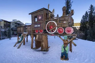 a person standing in front of a wooden play structure in the snow at Winter Park Chalet I Mtn Biking I Summer festivals in Winter Park