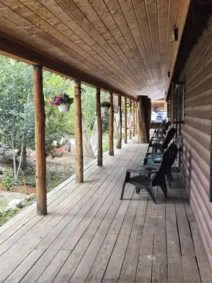 a row of benches sitting on a wooden porch at Black Bear Studio in Tranquil Courtyard by Grand Luxe in Grand Lake