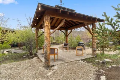 a wooden gazebo with chairs and a grill at Cozy cabin Steps from Lake and Board walk, 5 min RMNP, Moose Lodge Studio in Grand Lake