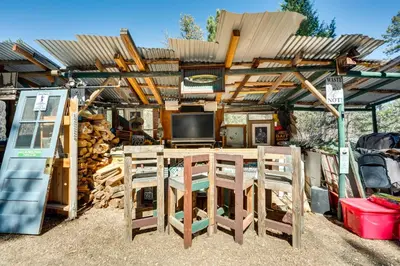 a wooden pergola with a table and chairs at 4 Mi to Estes Park Riverfront Cabin with Hot Tub! in Drake