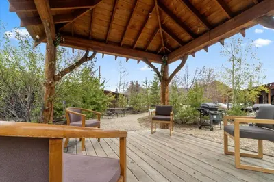 a wooden deck with chairs and a picnic table at Elk Run cabin steps to lake, In town, 5 min to RMNP in Grand Lake