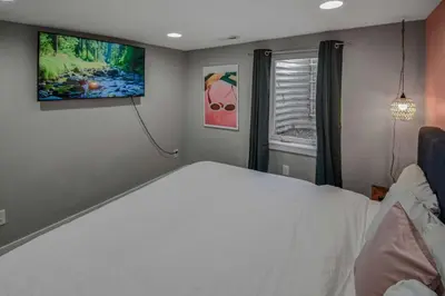 a bedroom with a white bed and a flat screen tv at Fun and Affordable Dual Bedroom Lower Unit in Vibrant Denver in Denver