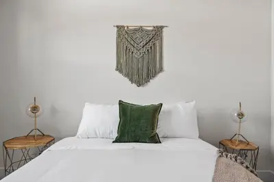 a bedroom with a bed with white sheets and green pillows at Mile High Muse Lifestyle Loft Espadin LoHi in Denver