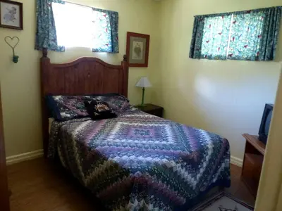 a bedroom with a bed with a colorful blanket at Rural Cabin Rental in Gorgeous Poudre Canyon near Fort Collins, Colorado in Fort Collins