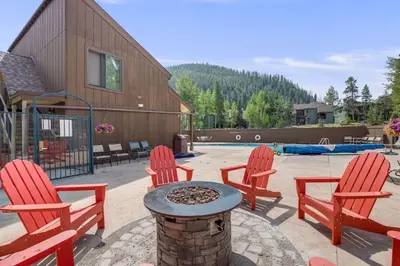 a patio with four red chairs and a fire pit at Rock Wren Poolside - 3 BDR Condo in Keystone