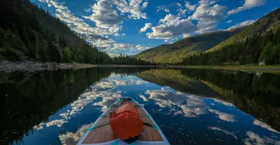a boat on a river with its reflection in the water at Base Camp One 410,0018 in Granby
