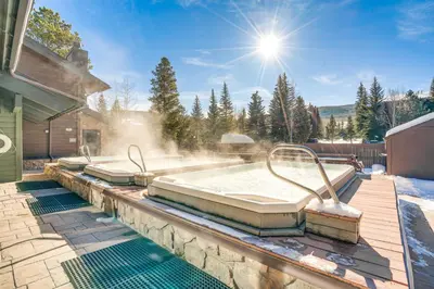 a hot tub on a patio with snow and the sun at half Mi to Dtwn Frisco Mtn-View Condo with Pool! in Frisco