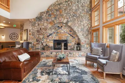 a living room with a stone fireplace and leather furniture at Expedition Station 8633 in Keystone