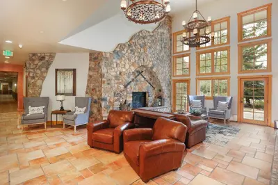 a living room with a stone fireplace and leather chairs at Expedition Station 8553 in Keystone