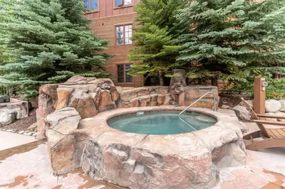 a large stone pool with a spa in a yard at Springs 8845 in Keystone