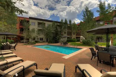 a pool with chairs and umbrellas next to a building at Expedition Station 8576 in Keystone