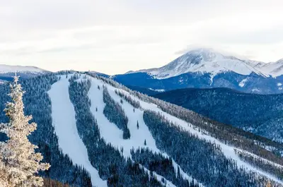 a view of a snow covered mountain range with trees at Expedition Station 8571 in Keystone