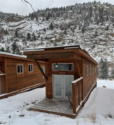 a log cabin with a door in the snow at Spring Gulch Cabin at Base Camp in Dumont