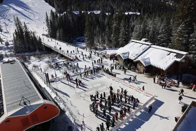 a group of people standing in the snow near a ski lodge at Kindred Resort Luxury Ski In, Ski Out 2 Bedroom Residence At The River Run Gondola in Dillon