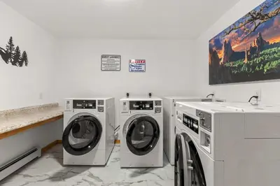 a laundry room with two washing machines and a painting at Cabin 21- Accessible Unit & King Bed in Estes Park