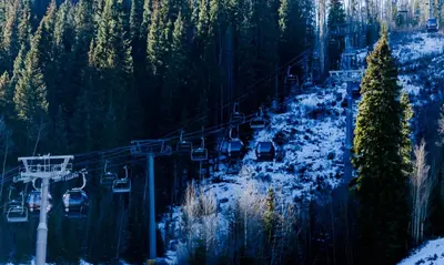 a ski lift in the middle of a snow covered forest at Lakeshore 1 in Keystone