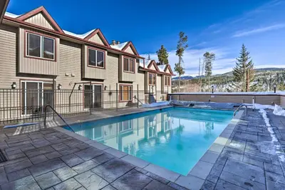 a swimming pool in front of a house at Ski, Soak and Chill! Pool-View Winter Park Condo in Winter Park