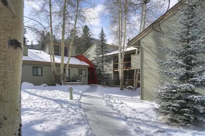 a snow covered yard with a house and a christmas tree at Flying Dutchman 1132 by SummitCove Lodging in Keystone