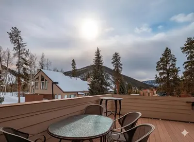 a patio with a table and chairs on a deck at Quicksilver 1609 by SummitCove Lodging in Keystone