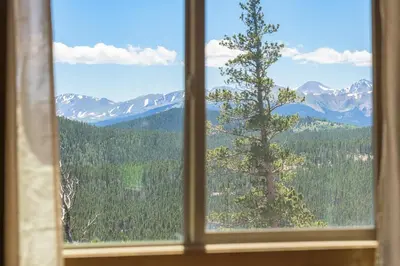 a window with a view of a tree and mountains at Skyline Lodge with Private Sauna & Hot Tub in Idaho Springs