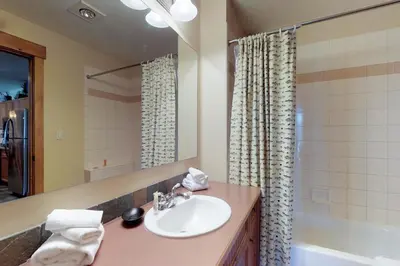 a bathroom with a sink and a mirror and a tub at Springs Lodge 8888 in Keystone