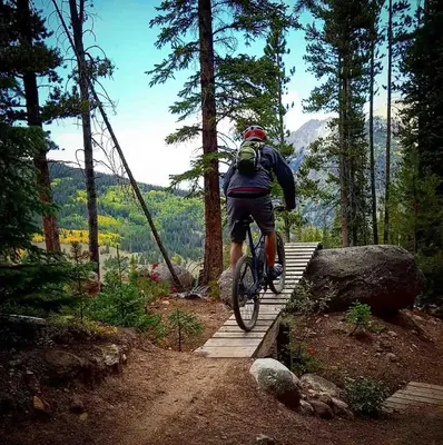 a man riding a bike on a wooden trail at Crossroads Snowshoe Townhome: Great Views, On Rec Path in Summit Medical Center Heliport